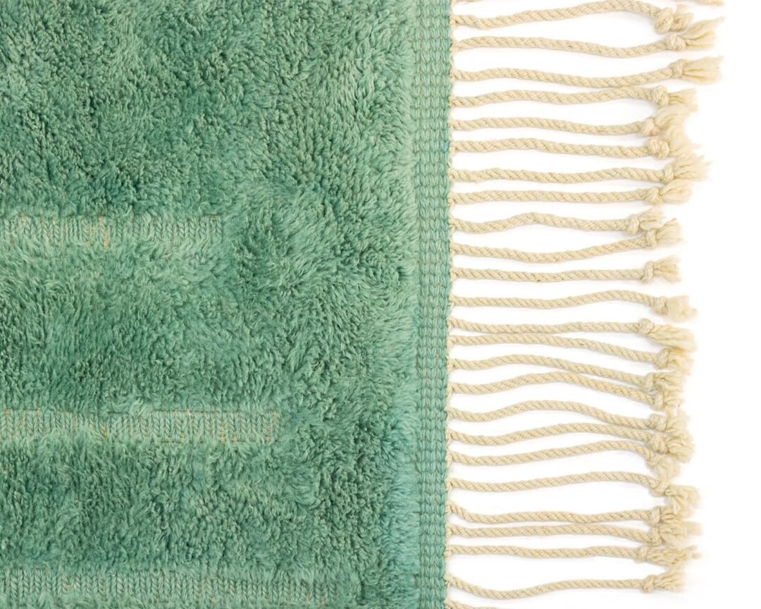 Green Moroccan hand knotted rug featuring a subtle abstract pattern that mimics organic shapes, Ivory fringes detail