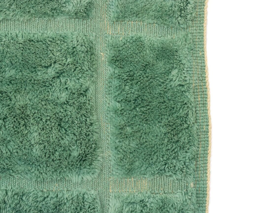 Green Moroccan hand knotted rug featuring a subtle abstract pattern that mimics organic shapes, detail photo