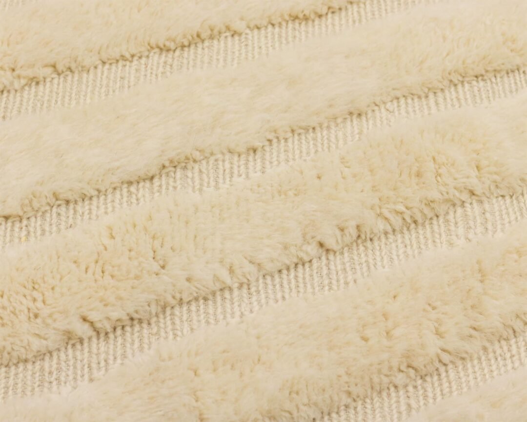 The close-up of the textured fabric features alternating raised and flat beige stripes, creating a plush, soft appearance that is both inviting and elegant.