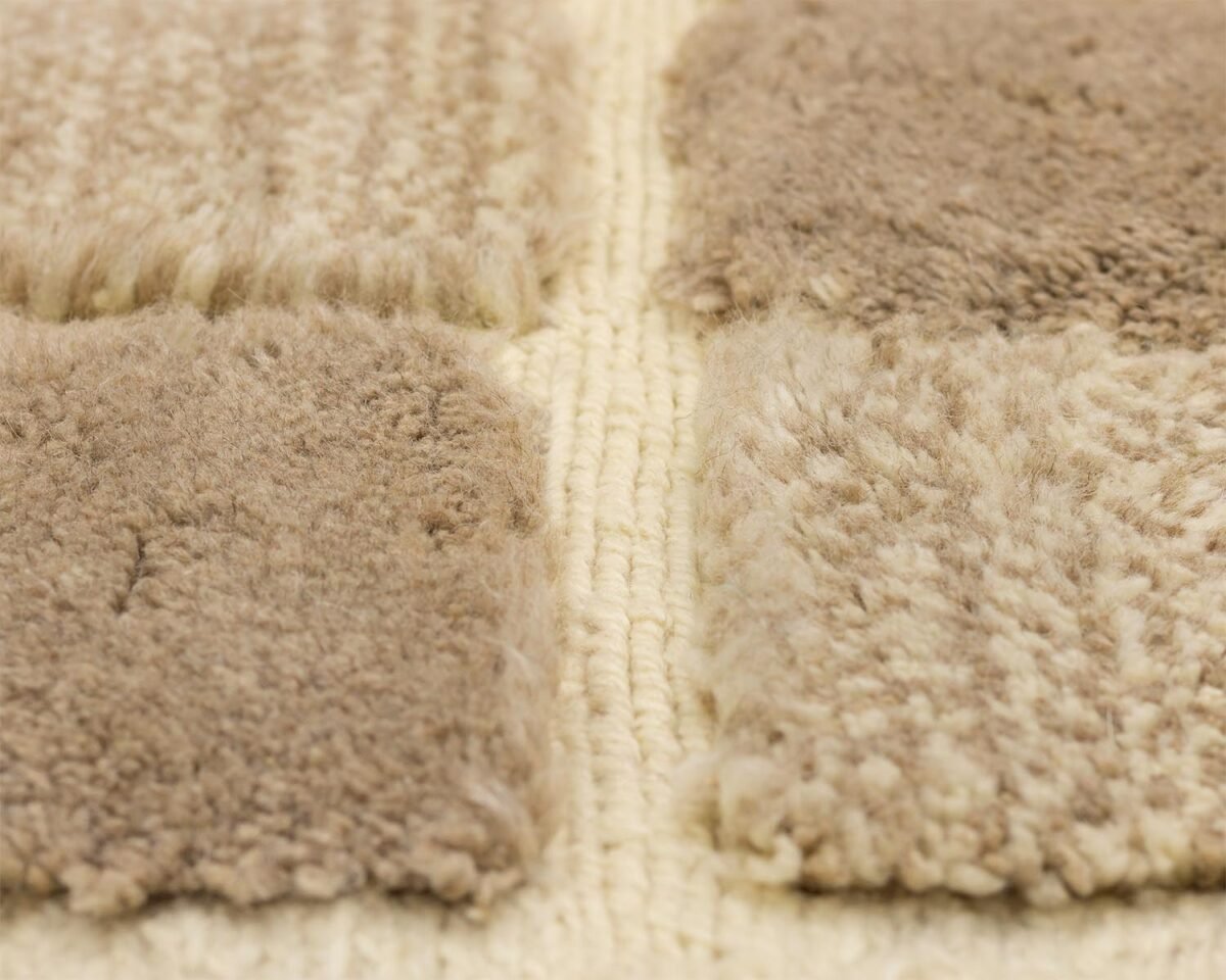 Close-up of beige and brown textured carpet samples arranged in a grid pattern against a light woven background, showcasing a harmonious blend of natural tones.