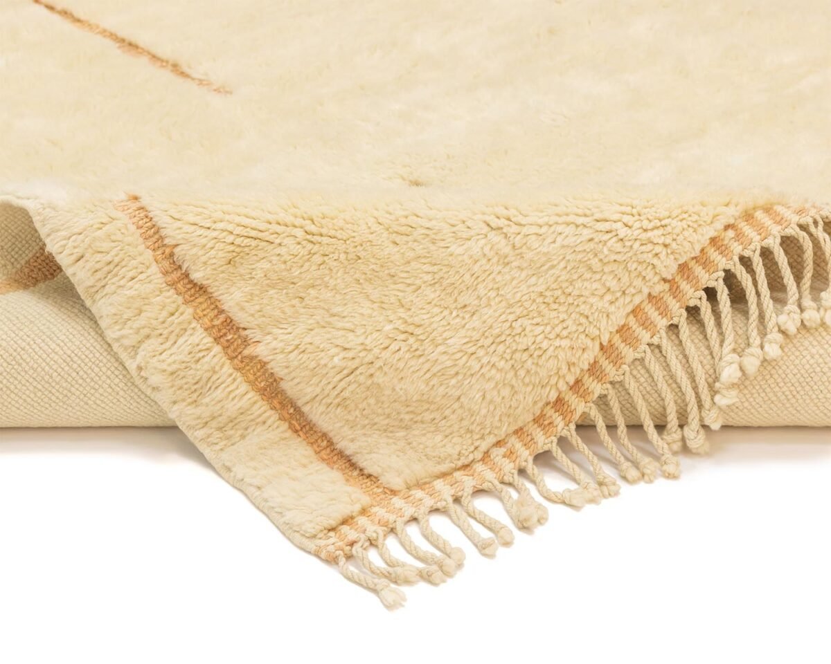 A close-up of a beige fringed Moroccan rug with brown stripes, showcasing its hand-knotted texture and intricate pattern.