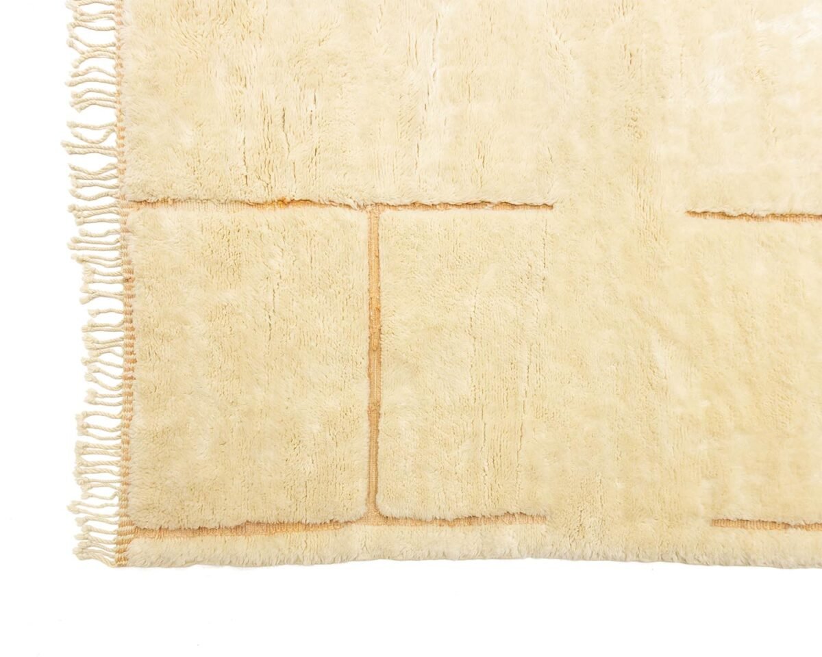 Moroccan rug with textured patterns and fringe on one edge, showcasing a luxurious touch in a beige hue.