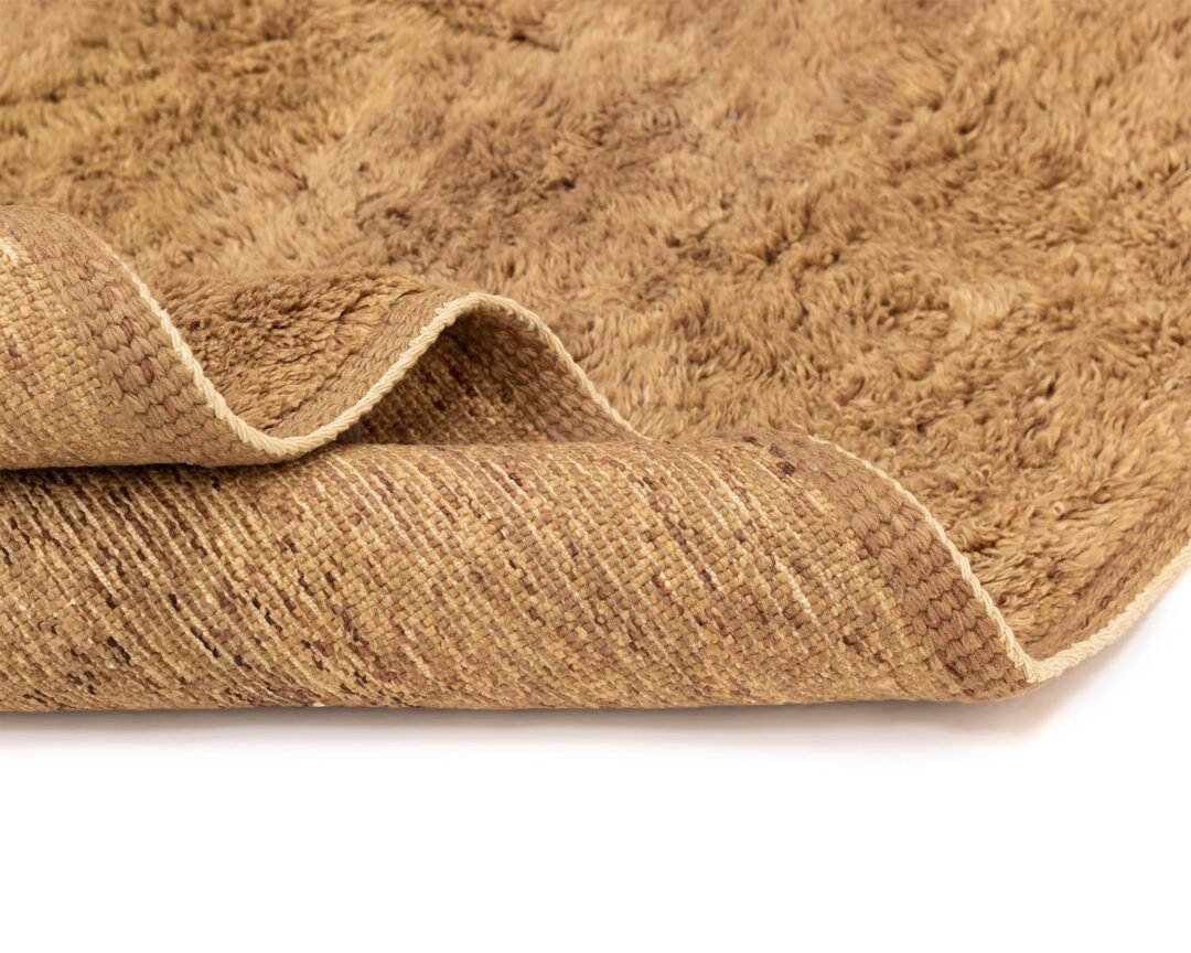 A close-up of a brown shaggy rug with a folded corner reveals its intricately woven underside, highlighting the craftsmanship and texture.