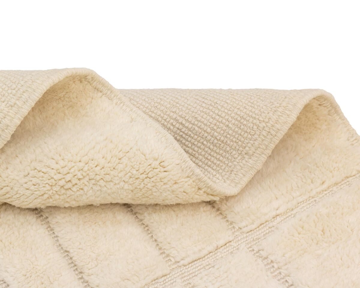 Close-up of a beige, textured towel with a folded corner, displaying a grid pattern and intricate details, perfect for adding style to any bathroom.