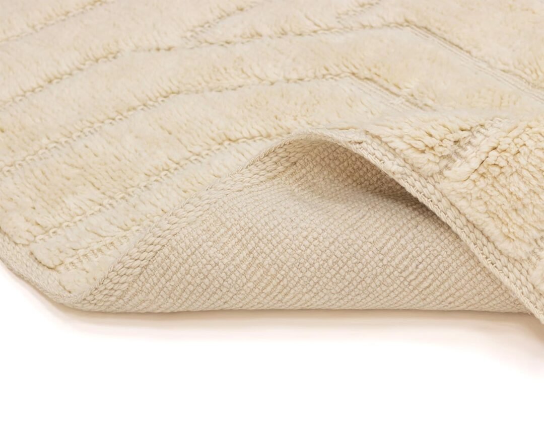 Close-up of a folded beige textured rug highlighting its woven underside and plush, inviting top surface.