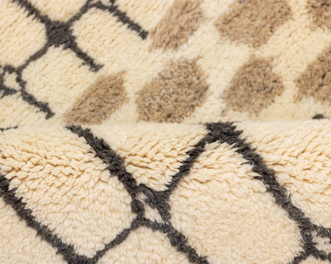 Close-up of a cream and brown fleece fabric with geometric patterns, resembling a hand-knotted Moroccan rug with its intricate diamond design.