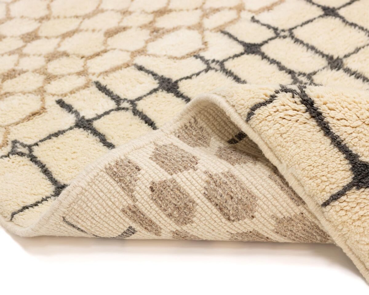 Close-up of a beige and black luxury Moroccan rug with the corner folded to reveal the intricate underside.