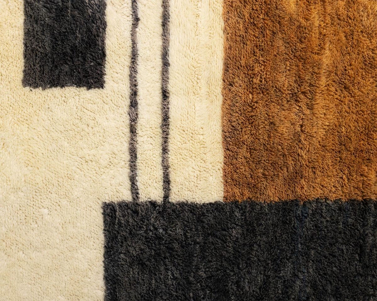 Close-up of a rug featuring geometric patterns in black, cream, and brown, adding a striking visual element to any space.