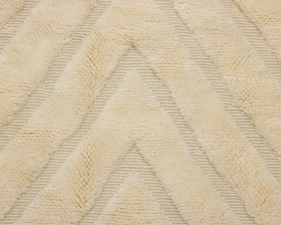 A close-up of a textured, cream-colored fabric reveals a zigzag pattern and plush, fluffy surface, giving it an invitingly soft touch.