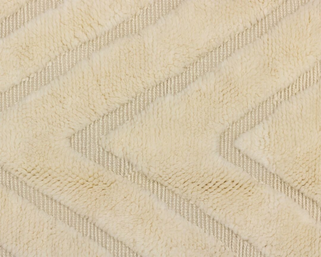 Heres a close-up of a textured beige and cream rug with an intricate zigzag pattern, adding a cozy touch to any space.