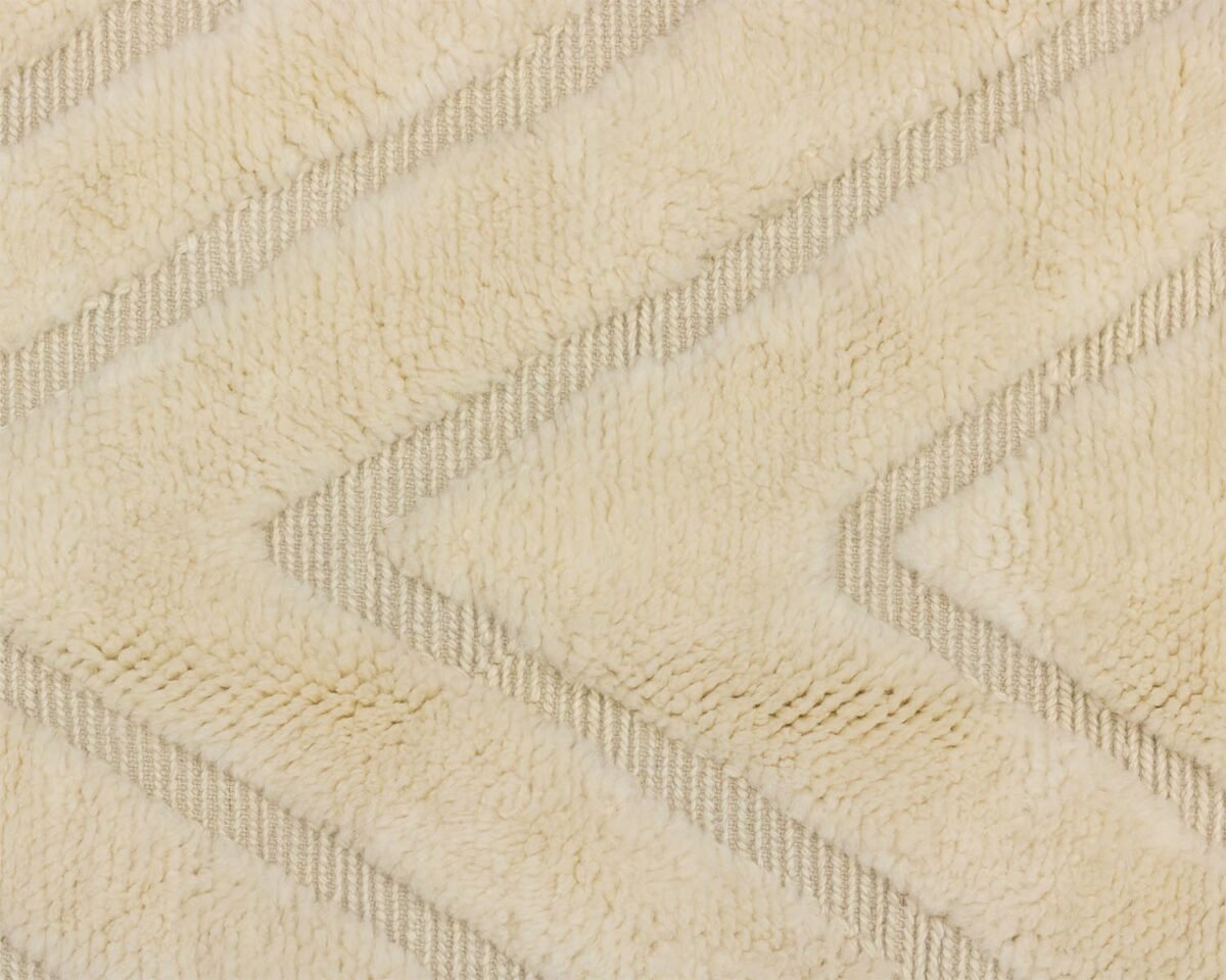 Heres a close-up of a textured beige and cream rug with an intricate zigzag pattern, adding a cozy touch to any space.