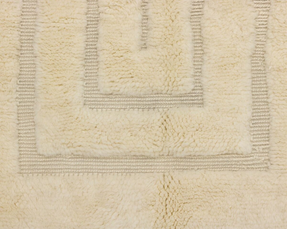 Close-up of a beige, textured carpet with a geometric design featuring raised, lighter, rectangular lines, adding a sophisticated touch to any space.