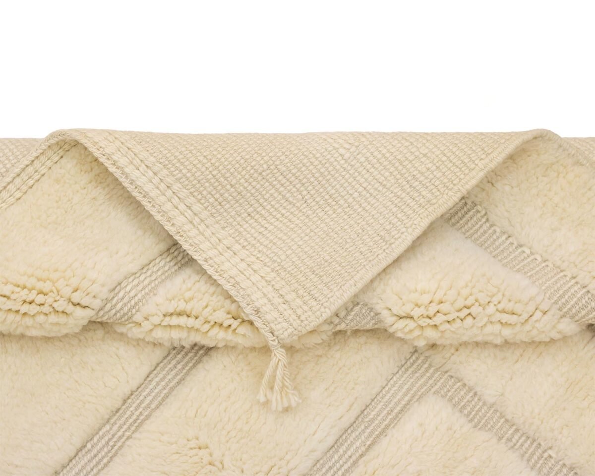 A folded beige textured throw with tassels, featuring a diamond pattern and a soft, fluffy underside.