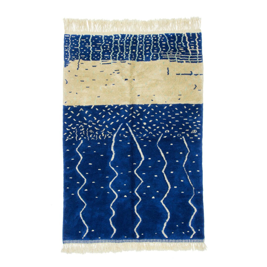 Moroccan rug with a striking abstract design in deep blue and cream, featuring textured patterns and wave-like forms across its surface.