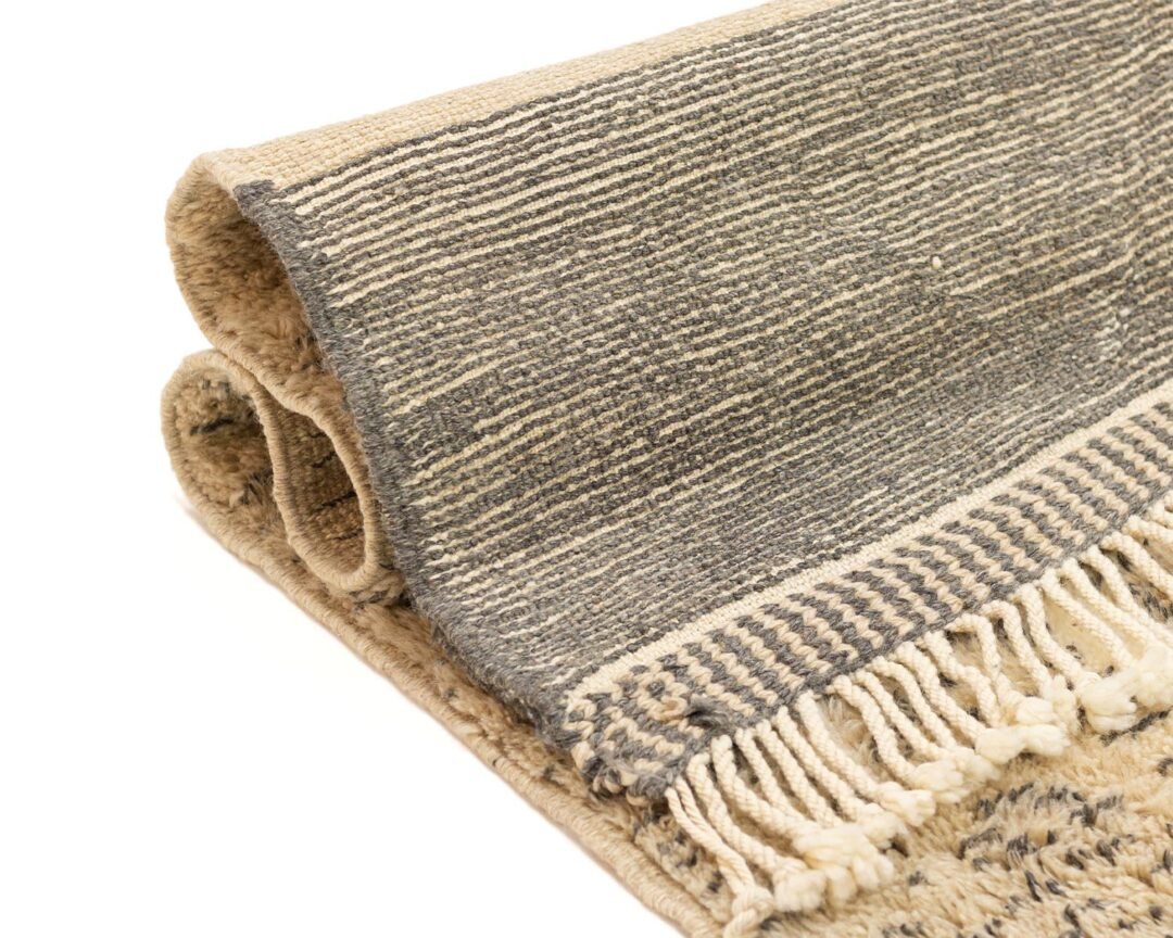 A woven rug in gray and beige boasts a striking striped pattern, enhanced by fringed tassels along its edges for a stylish touch.