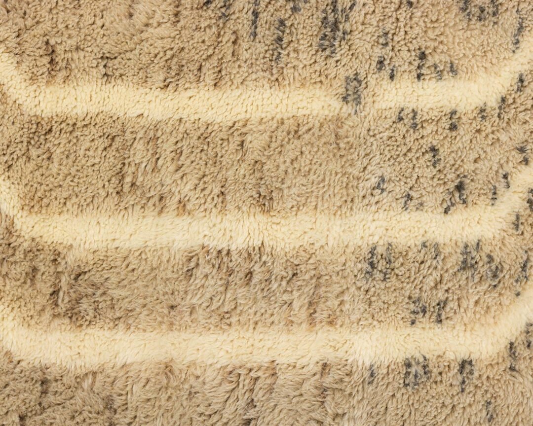 Close-up of a beige and brown striped fabric with a fluffy, tufted appearance, exuding warmth and coziness.