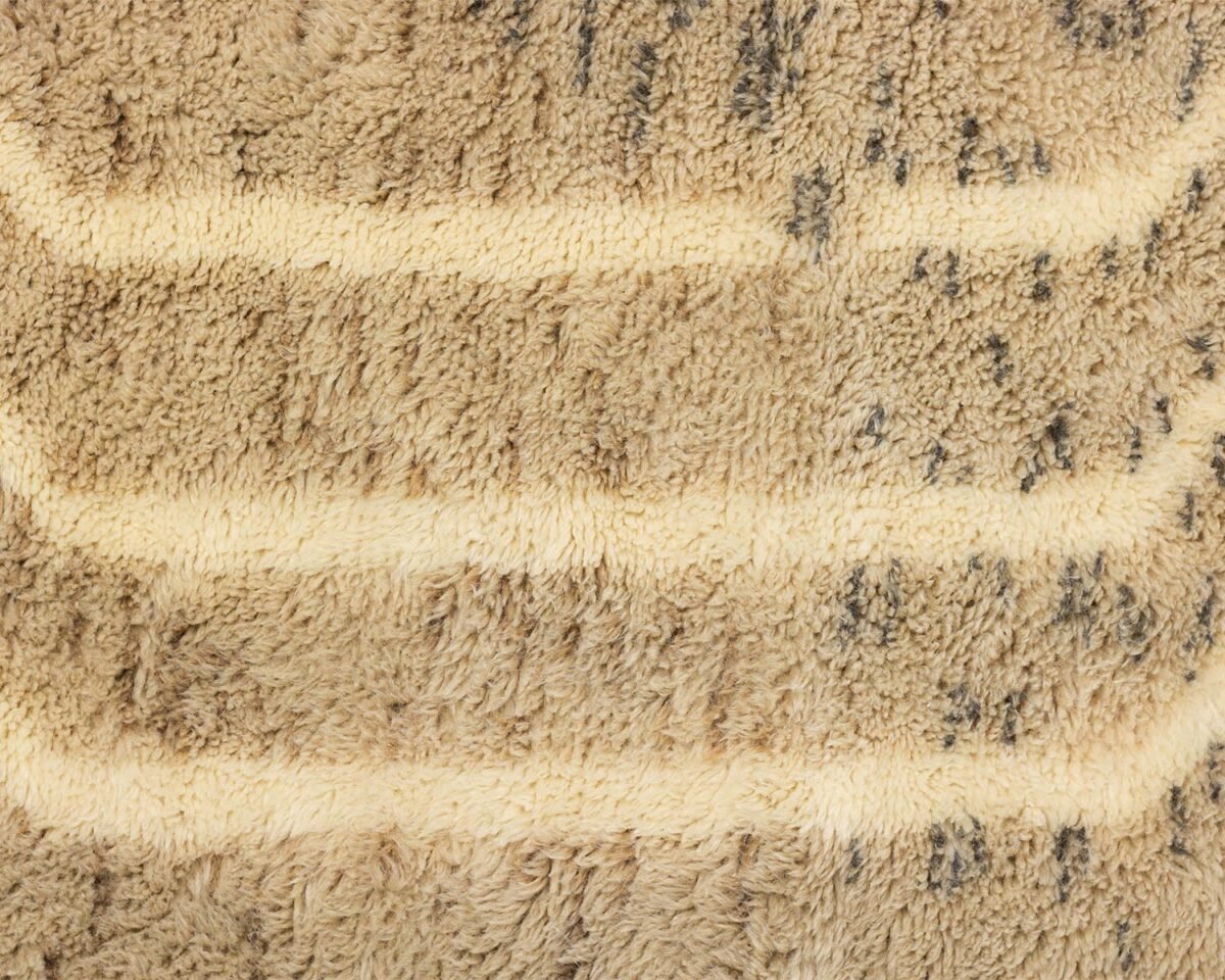 Close-up of a beige and brown striped fabric with a fluffy, tufted appearance, exuding warmth and coziness.