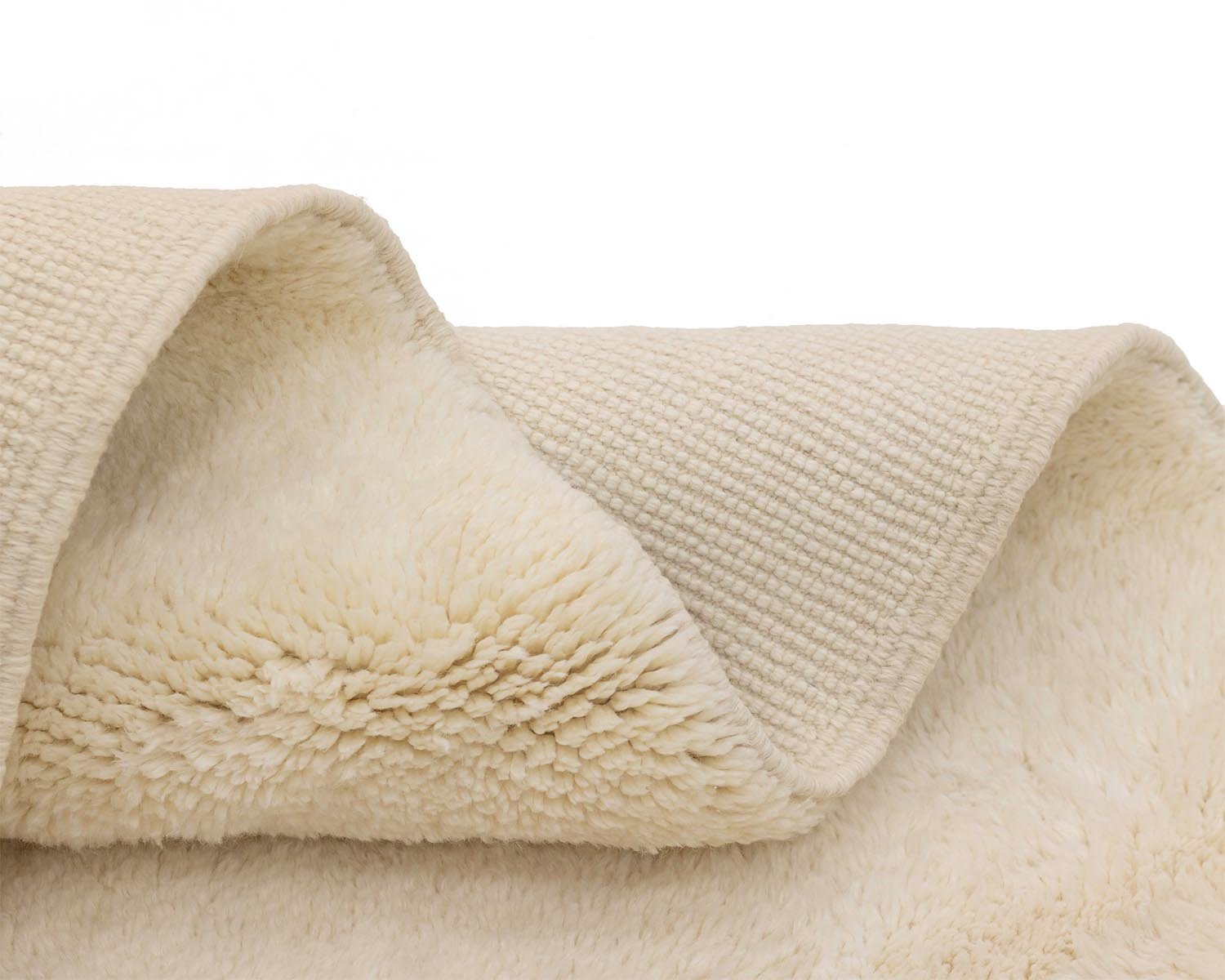 A close-up of cream-colored fleece fabric reveals a textured exterior and a cozy, fluffy interior for ultimate comfort.