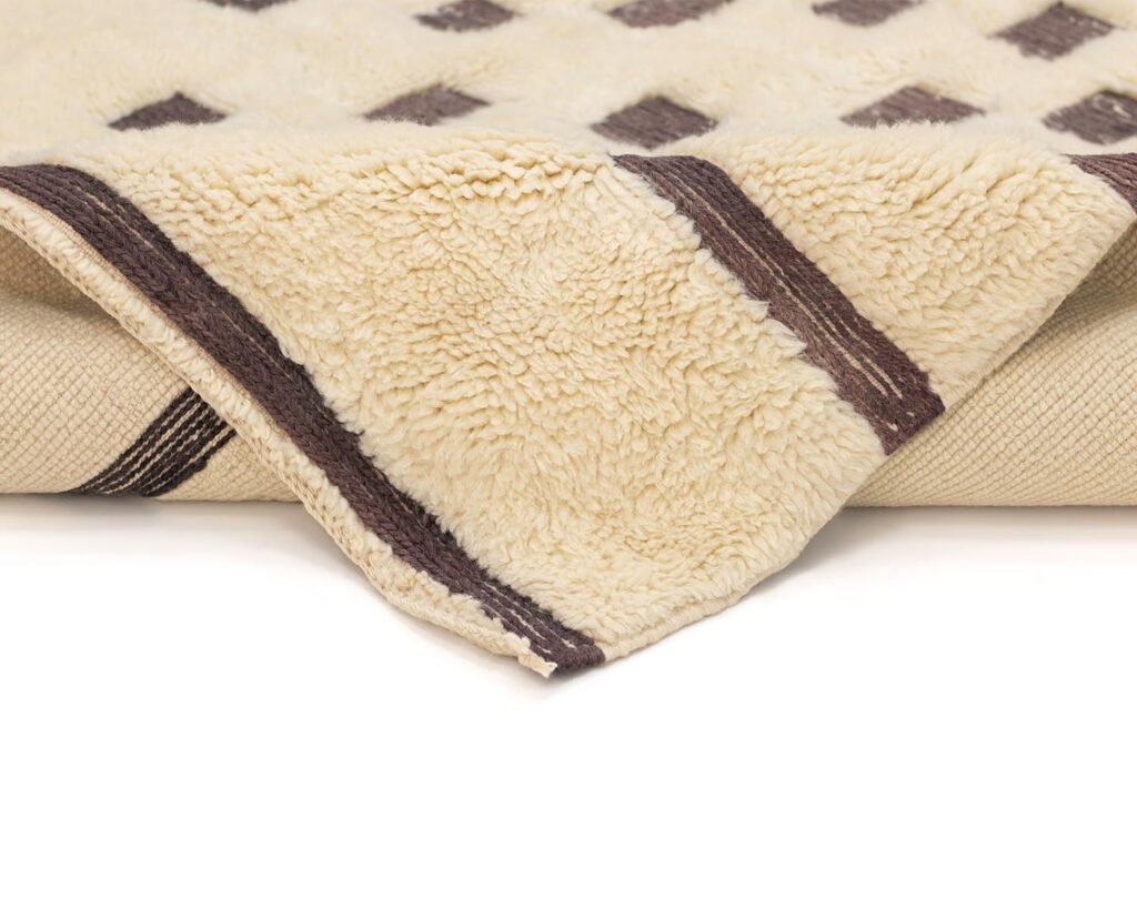 Close-up of a soft beige fleece showcasing a brown geometric pattern, folded over an elegant surface.