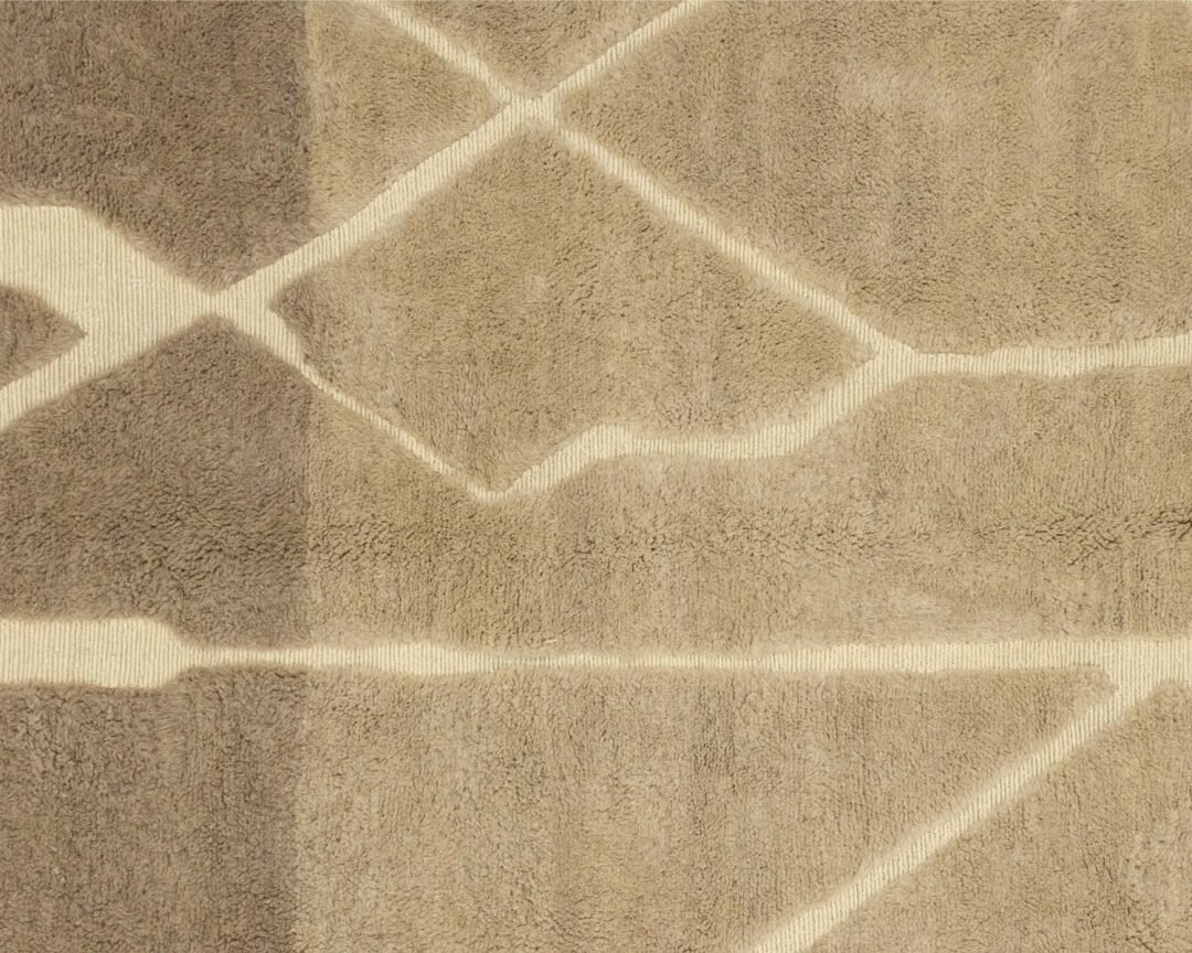 This luxury rug features a close-up view of its hand-knotted geometric pattern, showcasing intersecting lines and shapes in varying shades of beige. Perfect for adding an elegant touch to any room, it embodies the refined craftsmanship of handmade home decor.