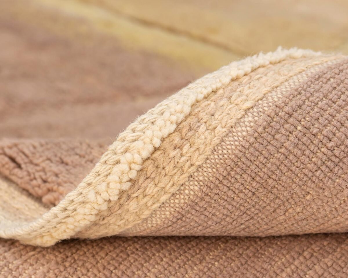 Close-up of a textured, beige woven fabric with a folded edge, reminiscent of a hand knotted Moroccan rug.