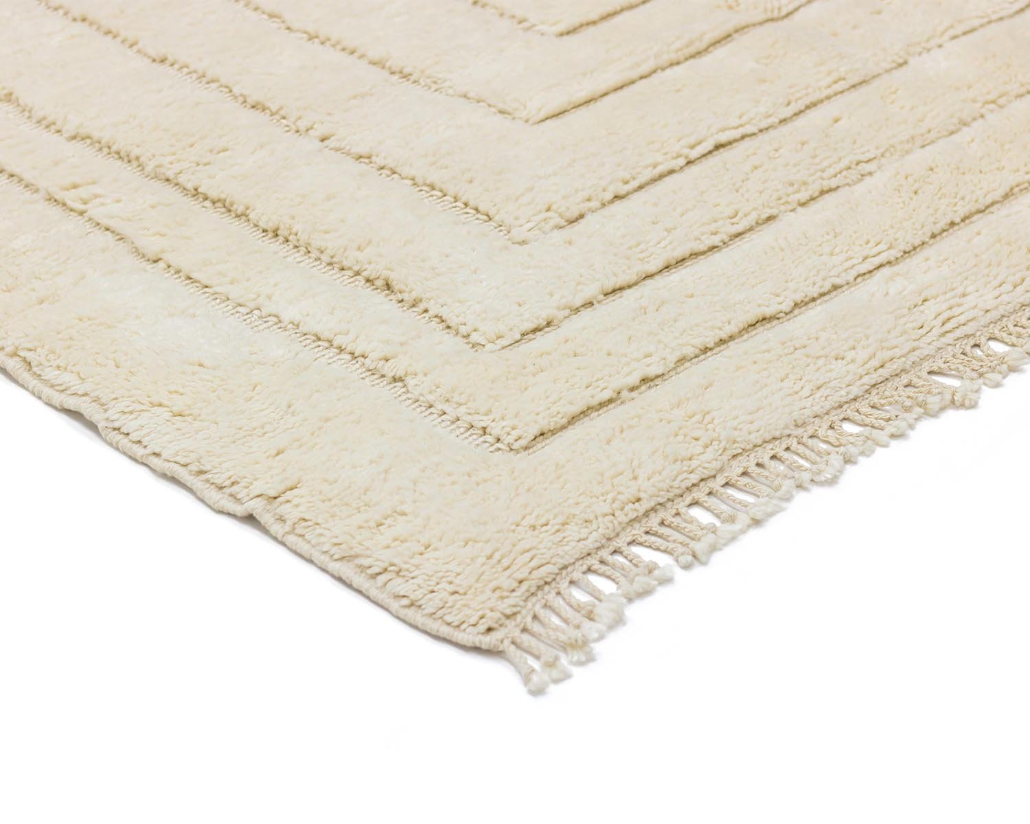 Close-up of a beige rectangular rug with fringed edges and a textured pattern, perfect for adding warmth and style to any room.