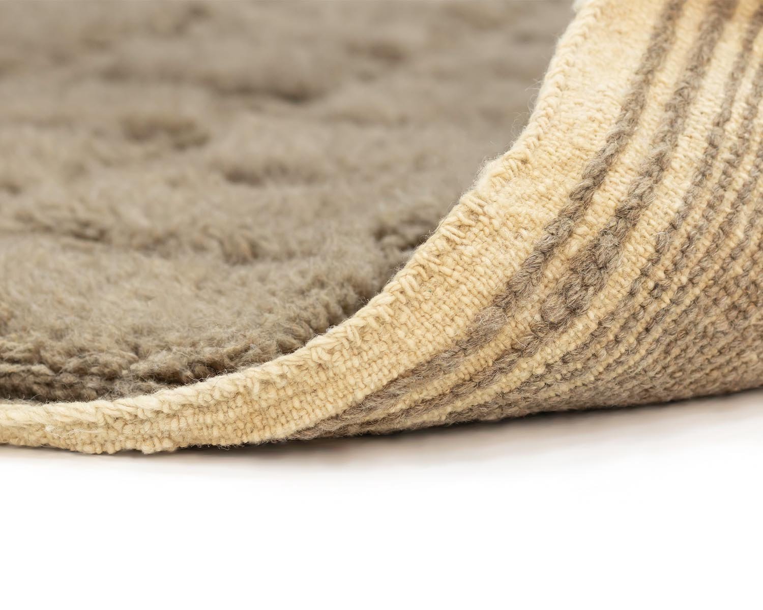 Close-up of a soft, fuzzy luxury rug corner folded over, revealing a textured underside on a white surface.