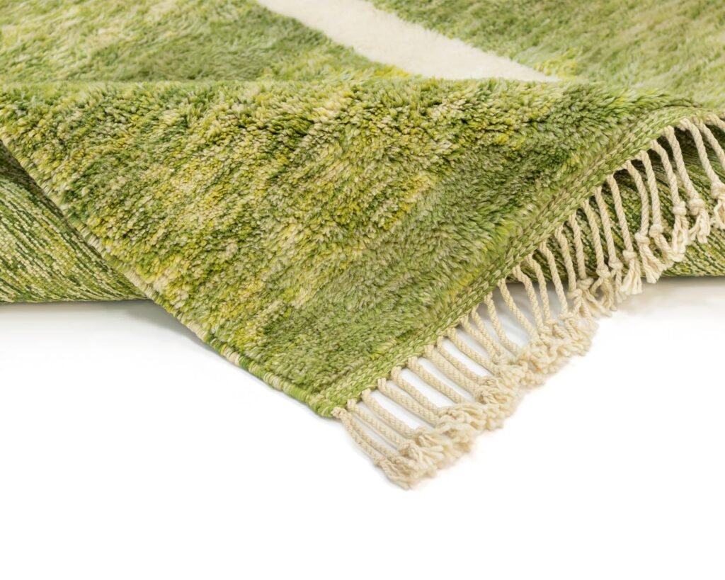 A green and white textured rug with fringe detailing on the edge, displayed on a white background.