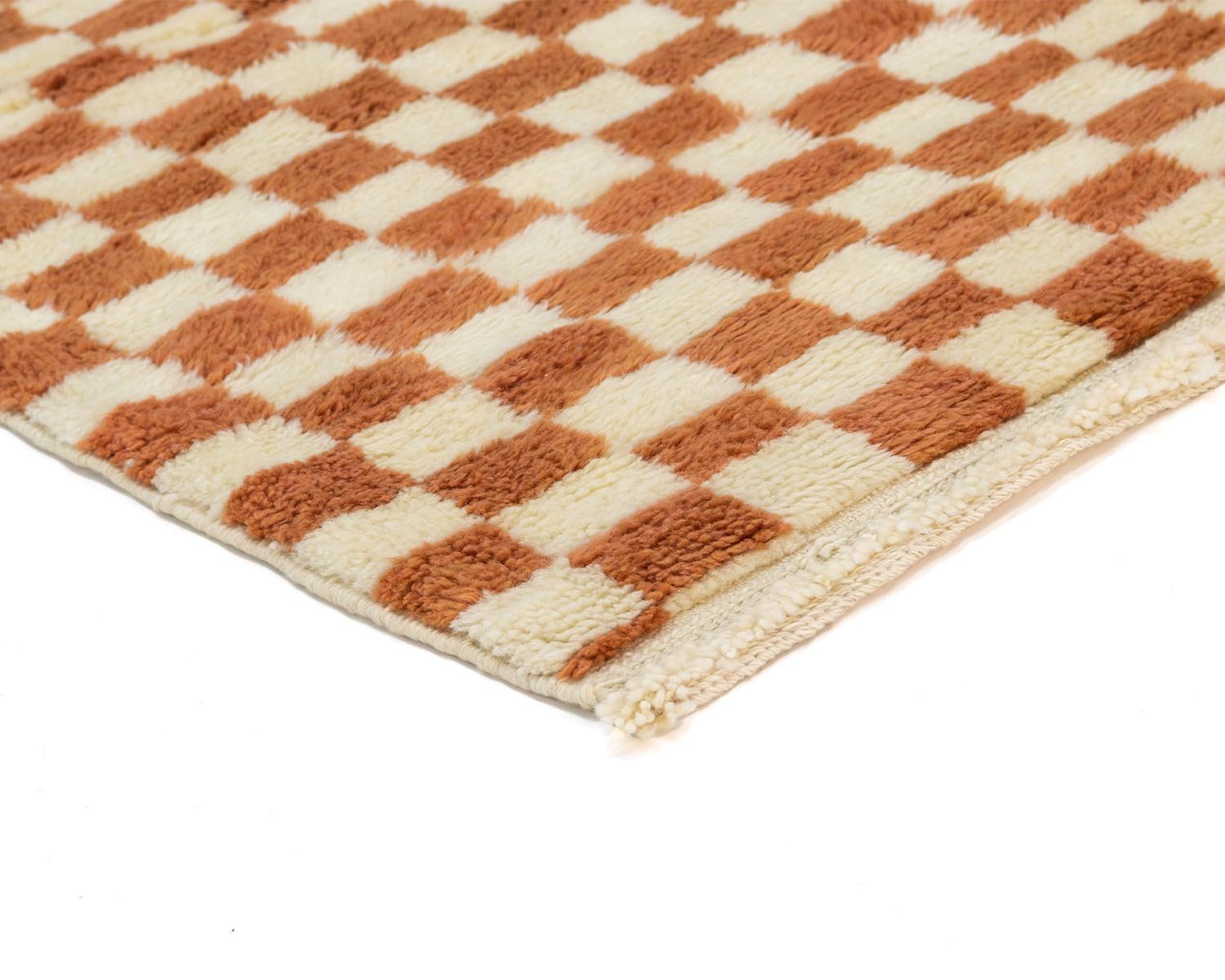 A close-up of a cozy, checkered fabric showcases a warm brown and beige pattern. The edge artfully contrasts against the white background, enveloping a sense of comfort.