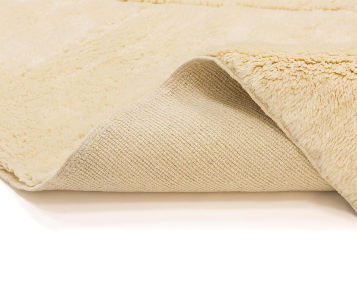 Close-up of a cream-colored fleece with a textured underside, partially folded to reveal the different textures, echoing the meticulous craftsmanship found in authentic Moroccan rugs.