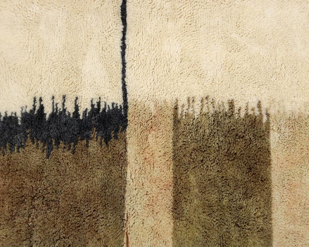 Close-up of a luxurious rug showcasing an abstract design with vertical black and brown shapes on a beige background. This exquisite piece is perfect for adding a touch of handmade home decor to any room.