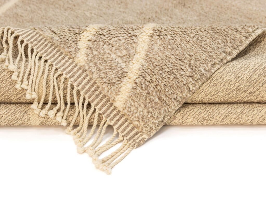 A folded beige woven throw with fringe detailing on one edge, featuring subtle diagonal stripes for a touch of elegance.