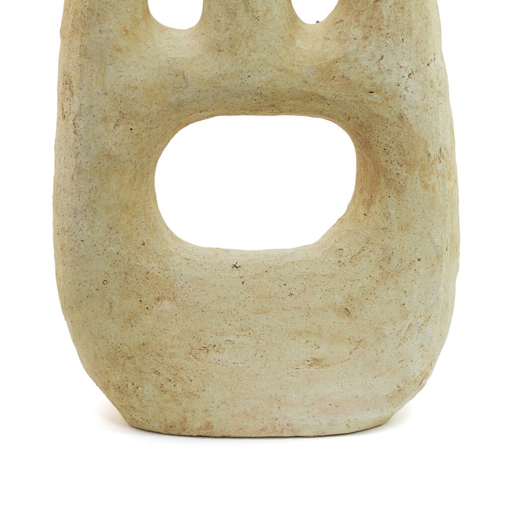 A beige stone sculpture reminiscent of unglazed Tamegroute pottery features four rounded protrusions on top and a large, oval hole in the center.