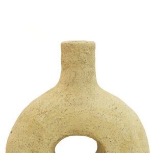 A textured, beige vase in the style of unglazed Tamegroute pottery, featuring a circular opening at the base against a plain white background.