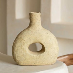 Beige, unglazed Tamegroute pottery vase with a textured finish, hollow center, and rounded top, elegantly placed on a smooth, light-colored surface.
