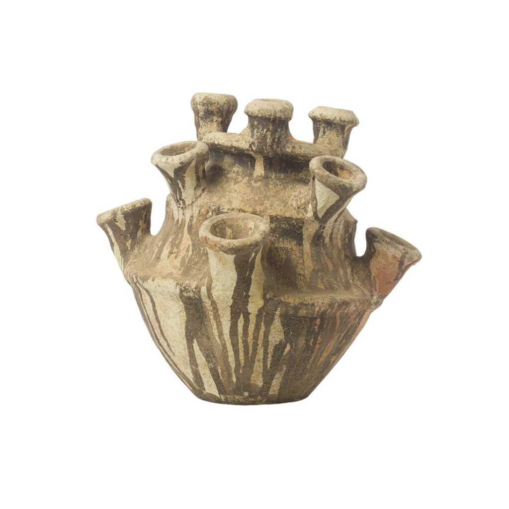 An unglazed Tamegroute pottery vessel, this ancient piece boasts a multi-spouted design with a wide base and numerous tubular openings. Its surface is rough and textured, showcasing the natural clay tones typical of its historical craftsmanship.