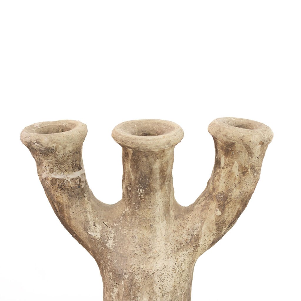 An ancient, three-branched, unglazed Tamegroute pottery vase with a weathered texture stands proudly against a plain white background.