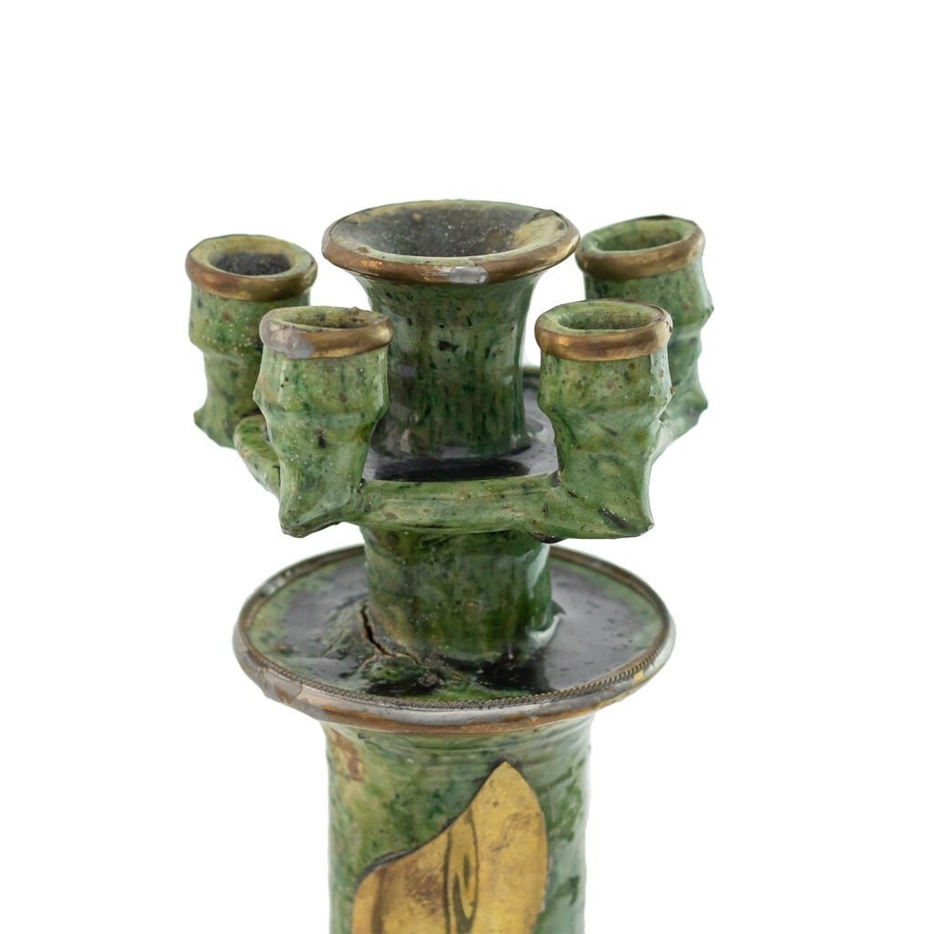This Tamegroute pottery piece is a green, multi-spouted ceramic object resembling bamboo. It features a single central opening surrounded by four smaller ones on top, showcasing the distinctive artistry of this traditional craft.