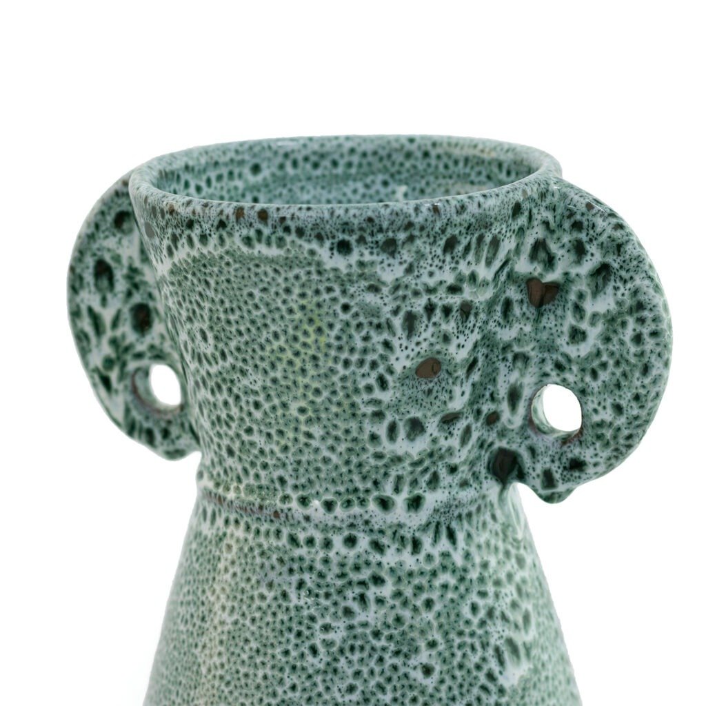 Close-up of a textured green ceramic vase with circular handles on both sides near the rim.