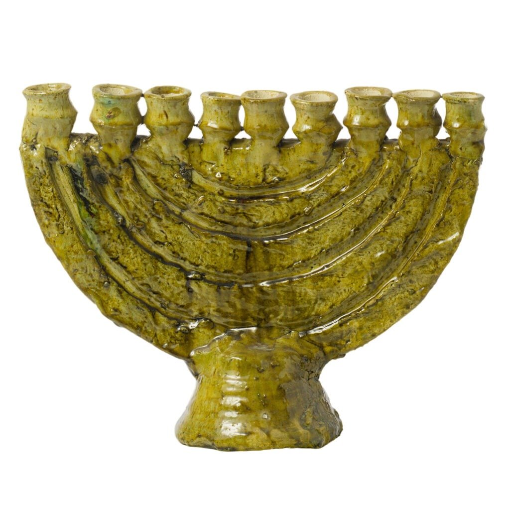 Green ceramic menorah with nine candle holders arranged in a semicircular pattern, featuring the textured, glazed finish typical of Tamegroute pottery craftsmanship.