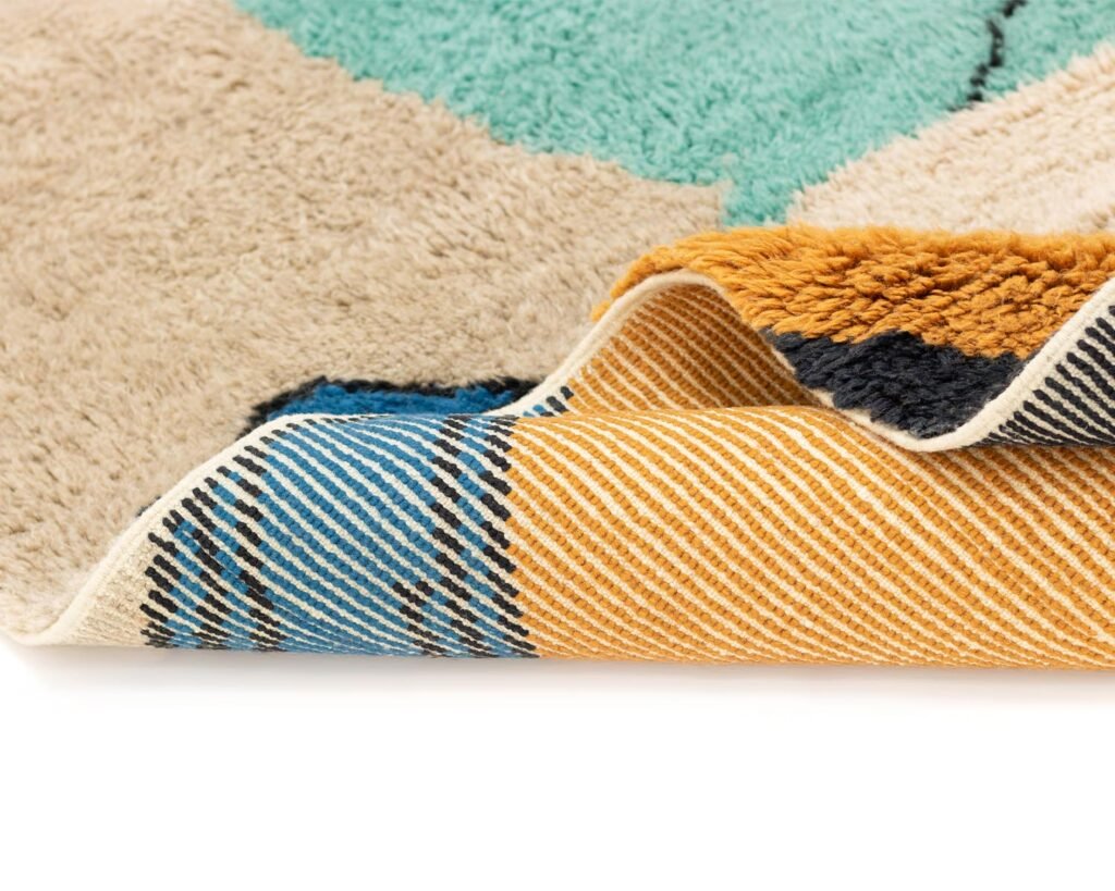 A close-up of a vibrant abstract-patterned rug reveals the intricately woven underside in striking stripes of yellow, blue, and black, adding a touch of artistic flair to any space.