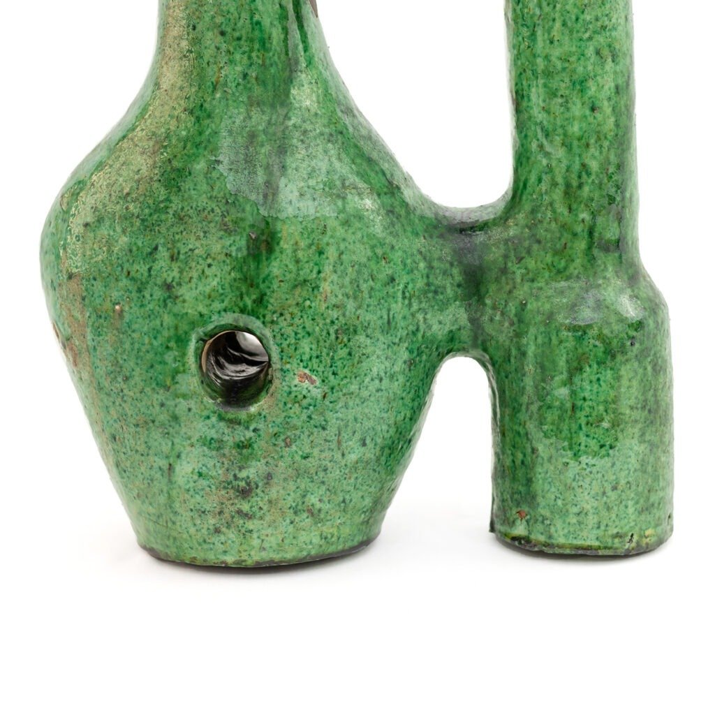 The green ceramic sculpture, resembling Tamegroute pottery, boasts abstract bulbous shapes and a small hole. Its textured finish and varying shades of green echo the intricate artistry found in traditional pieces.