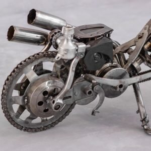 Close-up view of a handmade motorcycle sculpture crafted from various metal parts, including gears, chains, and pipes, all set against a neutral background—a perfect piece of home decor.