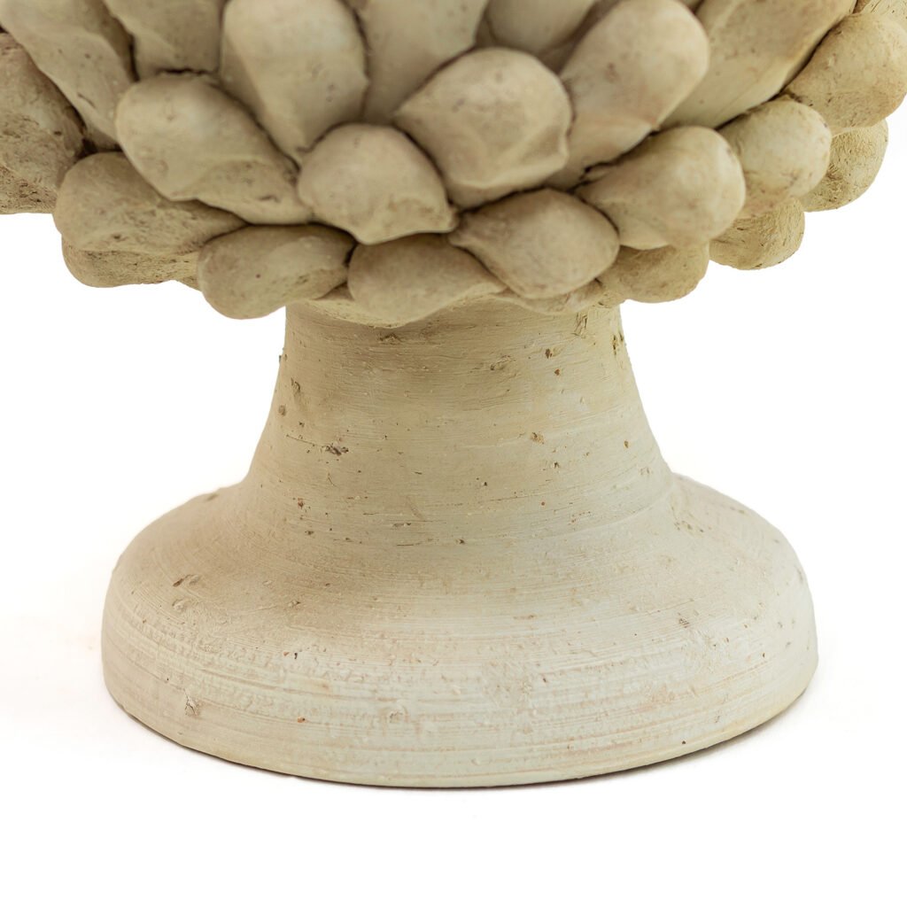 Close-up view of the base of a textured, light beige ceramic sculpture reminiscent of unglazed Tamegroute pottery, embellished with a round, patterned design.