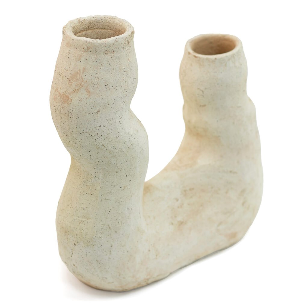 A cream-colored, abstract ceramic vase with two upward-curving, uneven cylindrical openings and a textured surface evokes the rustic charm of unglazed Tamegroute pottery.