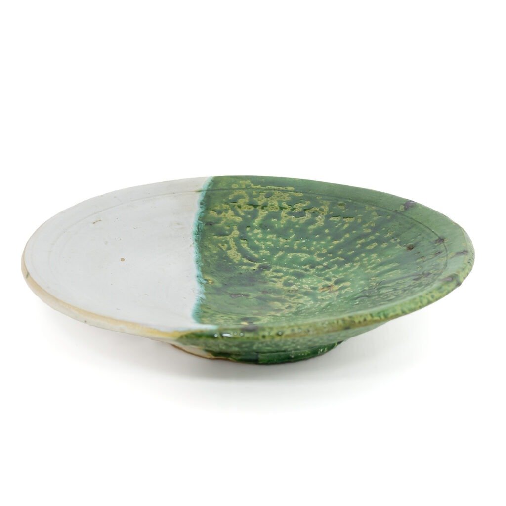 A round ceramic plate with a white and green design, this piece beautifully merges the essence of Tamegroute pottery. It features a textured, speckled green pattern on one half and smooth white on the other half.