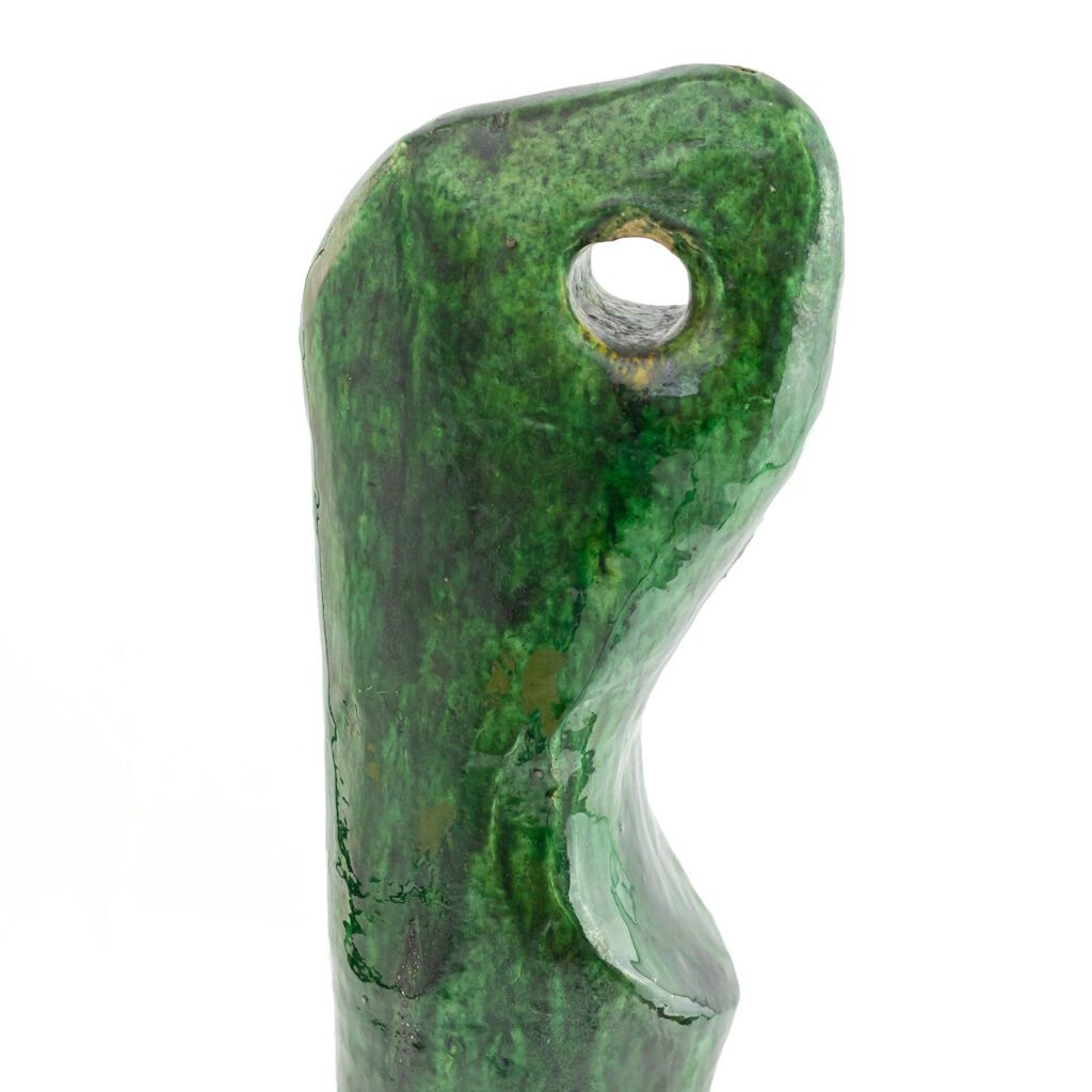 The green abstract sculpture, resembling Tamegroute pottery, features a glossy surface with a rounded form and a hole near the top.
