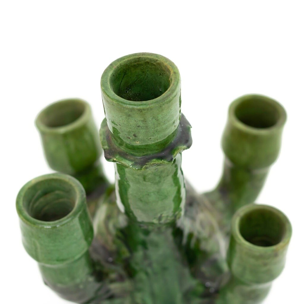 A close-up view of a green ceramic bottle with five spouts arranged in a circular pattern showcases the unique artistry of Tamegroute pottery.