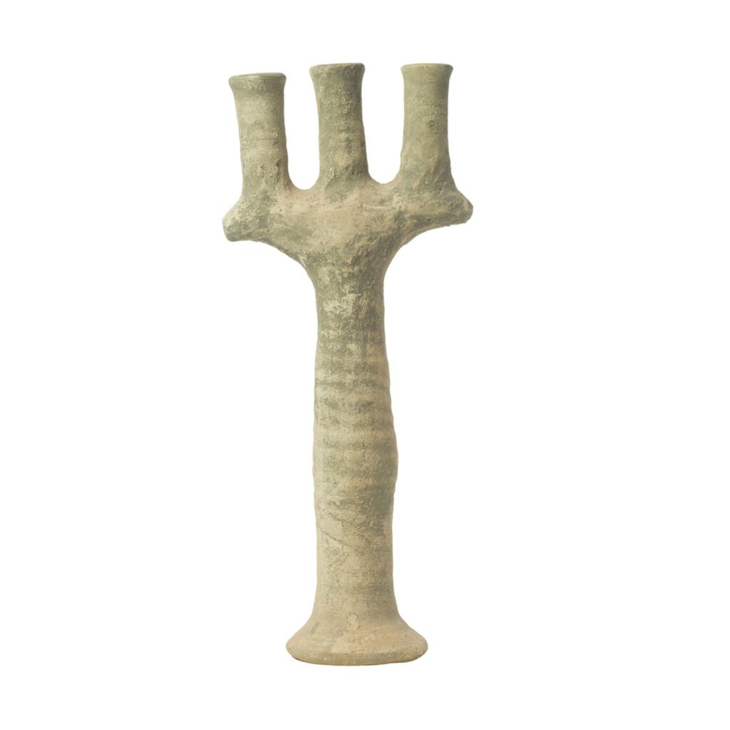 This ancient, unglazed Tamegroute pottery piece features a three-branched clay figurine with a textured surface, standing upright on a circular base and resembling a stylized tree or candelabrum.