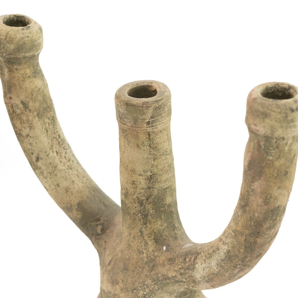 A three-pronged, rustic, unglazed Tamegroute pottery piece with a textured surface and hollow openings at each end extends upward.